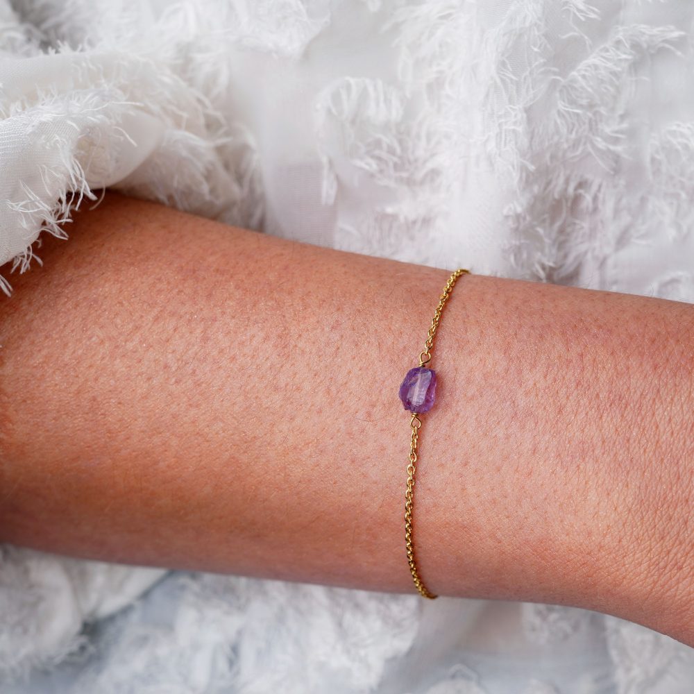 Pulsera de oro con un pequeño cristal en bruto de color violeta. Pulsera con pequeña piedra de Amatista en bruto en oro.